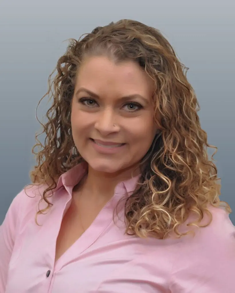 A woman with curly hair and wearing pink blouse