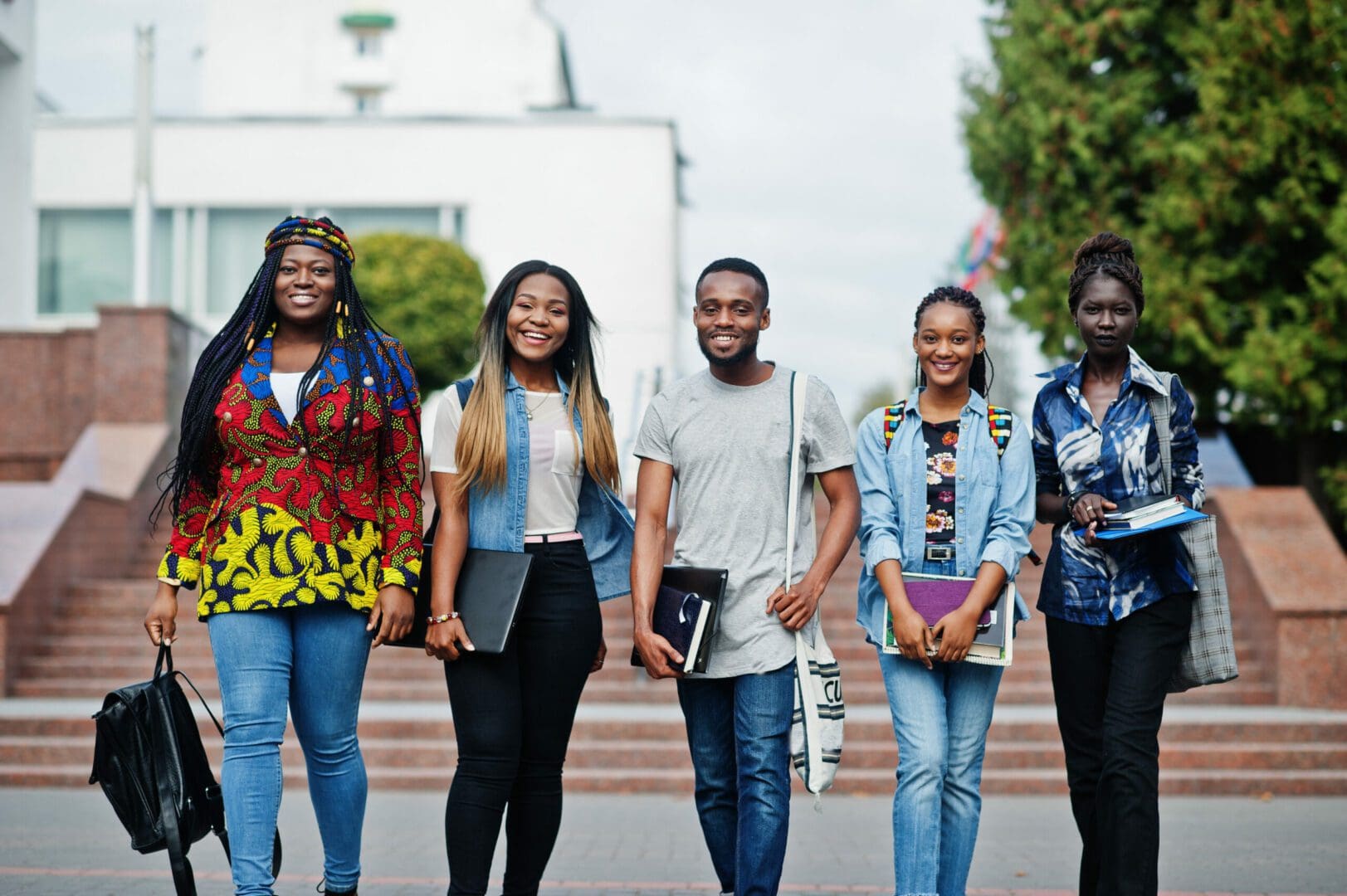 Group of five african college students spending time together on campus at university yard. Black afro friends studying. Education theme.