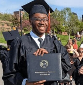 Graduate in cap and gown proudly holding diploma.