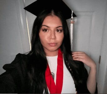 Young woman in graduation attire with cap and red stole.
